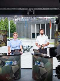 Eine Soldatin und ein Soldat stehen in einem Fernsehstudio