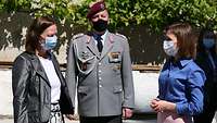 Deutsche Botschafterin und Staatspräsidentin Zwei Zivilistinnen und ein Soldat stehen nebeneinander.