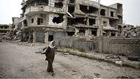 Eine Frau umgeben von Trümmern in Homs.