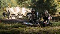 Two soldiers care for a wounded man during an exercise