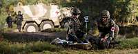 Two soldiers care for a wounded man during an exercise