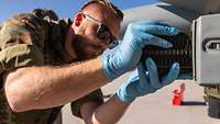 Ein Soldat mit Handschuhen schiebt ein Chaff-Magazin in den Dispenser am Eurofighter.