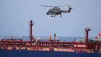 Ein Soldat wird mit einem Seil von Bord eines Schiffes in einen Hubschrauber hochgezogen