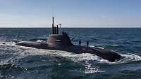 A dark grey submarine at sea.