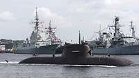 A dark grey submarine at naval base.