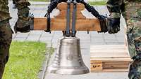 Zwei Soldaten tragen die neue Glocke zu ihrem Standort