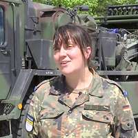 Eine Soldatin steht vor einem Lastkraftwagen.