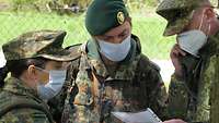 Drei Soldaten im Gespräch, einer hat ein Funkgerät am Ohr.