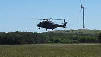 Der NH-90 landet auf der Fröttmaninger Heide Ein Helikopter landet auf einer Wiese, der Himmel ist blau und wolkenlos