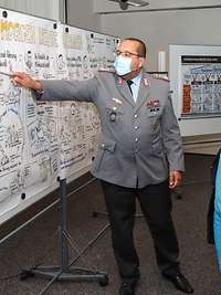 Vor einem Graphic Recording bringt Oberst i.G. Abed der Verteidigungsministerin das Projekt digitale Ausbildungsakademie näher