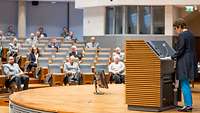 Verteidigungsministerin Kramp-Karrenbauer Die Ministerin steht auf dem Podium und hält die Grundsatzrede. Die Offiziere sitzen vor ihr im Auditorium und hören zu