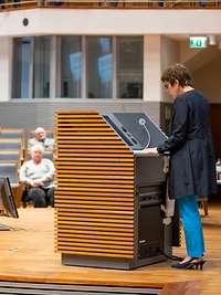 Die Ministerin steht auf dem Podium und hält die Grundsatzrede. Die Offiziere sitzen vor ihr im Auditorium und hören zu