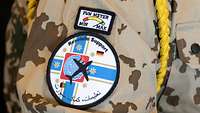 Im Bild sieht man einen Oberarm in Uniform und das Patch vom Lufttransportstützpunkt. Eine gelbe Kordel hängt über der Schulter.
