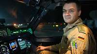 Ein Soldat in sandfarbener Uniform sitzt bei Nacht im Cockpit eines A400M.