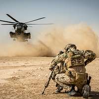 Ein SolSoldat kniet am Boden während Staublandung eines Transporthubschraubers CH-53