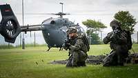 2 Soldaten kniend vor einem Helikopter