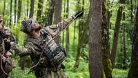 Ein Soldat mit einem Seil in der Hand setzt zum Wurf an einen Baum an