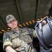 Soldat hält eine Kabeltrommel in der Hand.