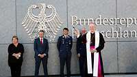 Segen durch den Militärbischof Eine Frau und drei Männer stehen vor dem Bundesadler. Davor segnet der Militärbischof mit Weihwasser die Flugbereitschaft.