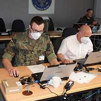 Ein Soldat und ein Ziviler Mitarbeiter sitzen nebeneinander an einem Tisch.