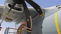 Ein Soldat befindet sich unterhalb des Propellers vom A400M und unterstützt bei der Nachflugkontrolle