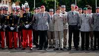Mehrere Soldatinnen und Soldaten stehen im Dienstanzug als Gruppe auf einem Appellplatz.