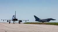 2 Kampflugzeuge auf betonierter Ebene rollen zur Startbahn