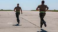 Zwei Soldaten rennen über eine betonierte Ebene