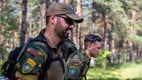 Zwei Soldaten marschieren mit Gepäck im Wald 