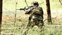 Ein Soldat feuert im Wald stehend auf Ziele.