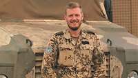 Ein Soldat steht vor einem Geländefahrzeug in einem Feldlager in Afrika.