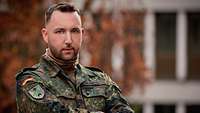 Ein Soldat hat die Arme verschränkt und blickt freundlich in die Kamera.