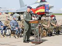 Generalleutnant Ingo Gerhartz steht an einem Rednerpult, im Hintergrund sitzen Soldaten