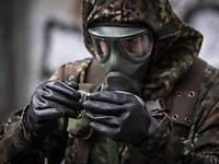 Ein Soldat in ABC-Schutzkleidung betrachtet ein kleines Glasröhrchen in seiner Hand