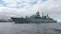 A grey ship is underway on a body of water.