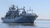 A grey ship is underway on a body of water.