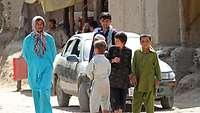 Zwei erwachsene Afghanen und vier Kinder auf einer nicht befestigten Straße