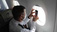 Ein israelischer Offizier filmt mit seinem Handy durch das Fenster des Flugzeuges