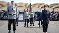 Ein Mann in Uniform und eine Frau stehen vor meheren Soldaten