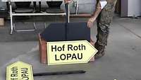 Ein Soldat stellt ein Schild in eine Transportkiste aus Holz.
