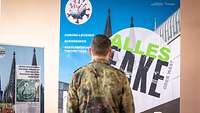 Soldat steht vor Plakaten.