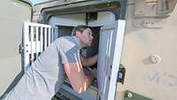 A man checking dog transport boxes in a vehicle