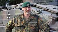 Ein Soldat steht vor einem Schützenpanzer