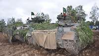 Zwei Schützenpanzer stehen nebeneinander auf sandigem Untergrund