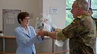 Ein Mann in Uniform übergibt ein Geschenk an eine Frau