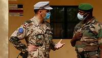 Ein deutscher Soldat unterhält sich mit einem malischen Soldat, dabei stehen sich beide gegenüber