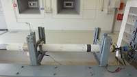 A rocket motor on the test stand A white tube is being mounted on a metal frame