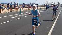 Marit Lorenzen läuft bei 35 Grad den abschließenden Marathon. Die Straße ist von Zuschauern gesäumt.