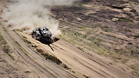 Der Leopard 2A6 der deutschen Kräfte bei voller Fahrt Vogelperspektive: Ein Panzer fährt über eine Sandpiste und zieht eine Staubfahne hinter sich her