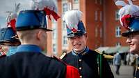 Ein Gruppe Soldaten in französischer Uniform sprechen auf einem Appellplatz miteinander.